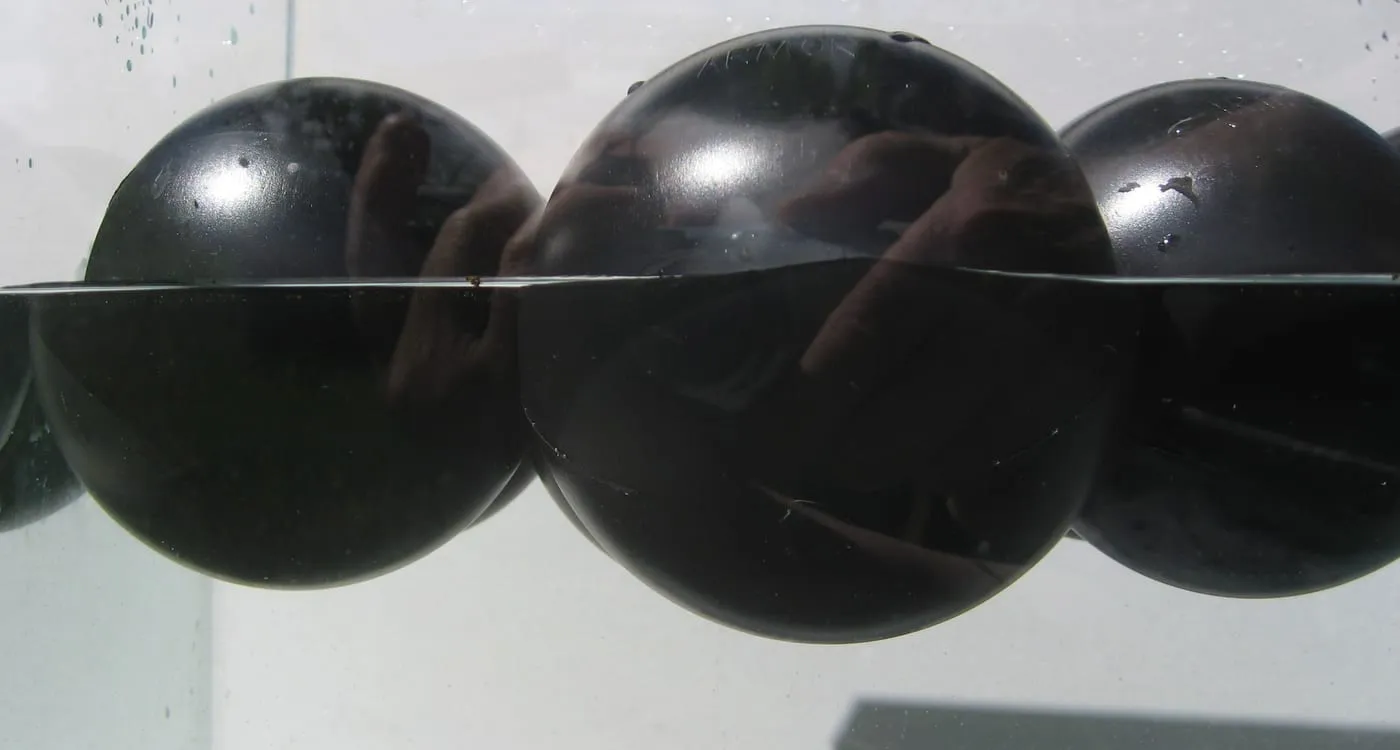 Cross-section view at the waterline showing Armor Ball® covers floating low on their pre-filled, sealed water ballast.
